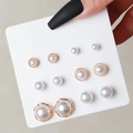 Detail view of six pairs of white pearl stud earrings on a card held by a hand - White Pearl Gold Trim Set (E0456-1)