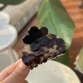 Nahaufnahme einer Haarklammer aus Acetat mit Schildpattmuster, schwarzer Blüte und Goldlogo - Schwarze Blume - Karamellpudding Marmor