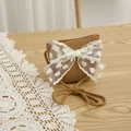 Detail of straw crossbody bag with white lace heart bow on a rustic wooden table - Bag-Khaki