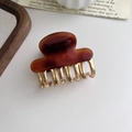 Minimalist acetate hair claw clip with golden metal teeth on white background - Dark Amber