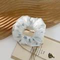 Detail eines doppellagigen Organza-Haargummis mit blauen Blumen und Netzstruktur - Blumenmuster Blau