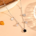 Macro view of silver necklace with floral pendants and black clover on wooden props - Silver Black Shell Necklace (C520)