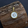 Golden round pendant with letter G and white mother of pearl shell on a wood log - Letter G / 17x20mm