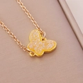 Golden chain necklace with a yellow acrylic butterfly pendant on beige textured cloth - Yellow