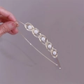 Macro detail of golden headband with rhinestones and five artificial pearls on grey background - Chain