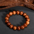 Bracelet en perles de bois naturel brun-rouge poli avec grain fin sur tissu sombre - Style Boucle Unique (12mm)