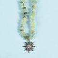 Light green irregular crystal bead necklace featuring a silver sun pendant on blue backdrop - Prehnite Sun