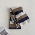 Sciarpa in maglia a righe marroni e blu scuro piegata su un piano con una rivista - Bianco Crema a Righe