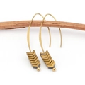 Detail of vintage gold arrow earrings hanging on a natural wooden branch background - Gold