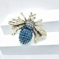 Vintage gold bee brooch with blue crystal wings and grey rhinestones on white pedestal - Style 31