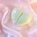 Two light green makeup sponges in a heart-shaped transparent case on pink silk fabric - Light Green Heart/OPP Bag