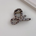 Dettaglio ravvicinato di un fermaglio per capelli leopardato con finitura lucida e molla - Stile Curvo Leopardo Chiaro