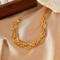 Gold chunky chain bracelet with mixed oval and braided links on beige satin display - Gold