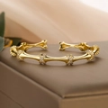 Gold plated bamboo joint open cuff bracelet with zircon accents on dark jewelry box - Gold
