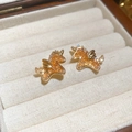 Dettaglio macro di orecchini a lobo unicorno placcati oro con cristalli di zirconia ambra - Oro/Marrone