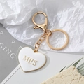 Porte-clés cœur doré minimaliste avec inscription Mrs en émail blanc sur fond déco - Cœur Blanc MRS