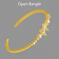 Gouden open armband met peervormige zirkonia stenen en een stijlvol vlinder ontwerp - Gouden open manchet armband
