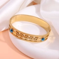 Detail of gold-plated evil eye bangle with hollow flower patterns on white silk background - Single Row Daisy Bangle