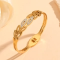 Close-up of gold hollow leaf bangle with white zircon inlays on a warm beige background - Gold Hollow Leaves Style (M811)