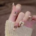 Detailed view of nude pink gradient press-on nails with crystal and pearl bow decor - Z627 Sweetheart / Nail Glue Version