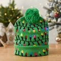 Detail of green knitted Christmas hat with glowing LED lights and top pom-pom on wood - Green With Color Lamp String