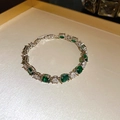 Elegant silver bracelet with green oval gemstones and clear crystals on a tray - Silver/Green