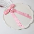 Pink satin ribbon bow hair clip with long streamers on a white decorative ceramic plate - Pink