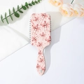 Detailopname van roze haarborstel met strikpatroon op een minimalistisch bloemendecor - C-Luipaard Strik