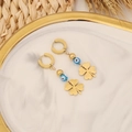 Dettaglio dei ciondoli occhio del male e quadrifoglio dorati su vassoio di marmo e luce - Design Fiore d'Oro