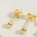 Polished 14K gold plated bead stud earrings with secure butterfly backs on white leather - 4MM Round Bead Stud Earrings
