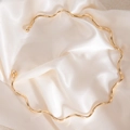 Collier rigide doré ondulé avec perles rondes sur fond de soie blanche élégante - Ras-du-cou en forme de vague dorée avec extrémités sphériques