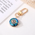 Macro detail of crystal evil eye keychain with blue rhinestones and gold-tone hardware - Gold Round Eye