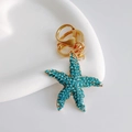 Starfish keychain with blue rhinestones and golden lobster clasp on a white tray - Basic Starfish / Blue