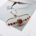 Detail of gold flower-shaped quartz watch with red gemstones and adjustable cord strap - Rose Gold Red