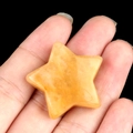 Handheld star-shaped yellow crystal stone with natural mineral texture on black backdrop - Yellow Jade