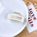 Macro detail of a matte cream square hair claw clip on a decorative ceramic plate - White