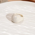 Close-up of a minimalist cream resin oval ring placed on a textured water-ripple tray - White Oval