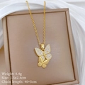 Detail van gouden vlinder ketting met kristallen op een beige juwelendoosje - Gouden Dubbele Vlinder Stijl (A412)