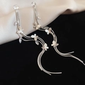 Detail van zilveren lange kwastjes oorbellen met vlinderbedeltjes en sprankelende zirkoon - Zilver (Zilveren pin)