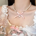 Détail du nœud en soie rose et pendentif cœur sur un collier de perles porté par un mannequin - Style Petit Coeur Argent Antique