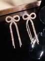Close-up of sparkling rhinestone bow earrings with long tassels on a black background - Stud Earrings / Gold AB Color
