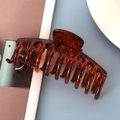 Close-up of a brown amber patterned plastic hair claw clip with multiple comb teeth - Glossy Amber Brushed 11cm