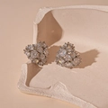 Detail von silbernen Herzohrringen mit Pavé-Zirkonia auf einer beigen Schale - Silbernadel - Silberne Zirkonia Herz Ohrstecker