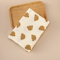 Detail of soft beige cotton muslin swaddle blanket with brown bear prints on wooden tray - 100x100cm / Bear Head