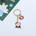 Détail d'un porte-clés de Noël doré avec pendentifs Père Noël et couronne sur fond blanc - Père Noël et Couronne