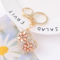 Macro shot of gold heart keychain with sparkling white crystals and pink rhinestone flowers - White Rhinestone Pink Flower Heart