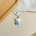 Dettaglio di un simpatico portachiavi a forma di orsetto con salopette blu su sfondo - Salopette (Cucciolo Bianco)