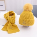 Gelbes Strickset für Kinder mit Bären-Stickerei und flauschigem Pompon in Nahaufnahme - Gelb