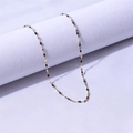 Detailed shot of a gold lip chain necklace featuring black oval beads on a purple fabric - Gold + Black / 40+5cm