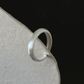Close-up of minimalist silver ring with brushed matte texture on stone pedestal - J3286 Minimalist Brushed Wide
